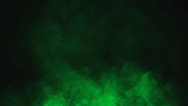 Ondas ondulantes de nubes de niebla de humo verde del hielo seco a través de la luz inferior. Niebla en el suelo aislado fondo negro textura —  Fotos de Stock
