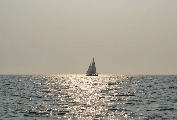 Sakin deniz ve güneşli gün parlayan suda yalnız Yelkenli teknede