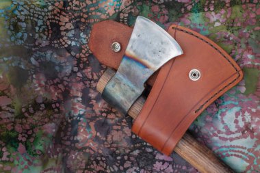 A leather sheath and hand forged tomahawk with color. clipart