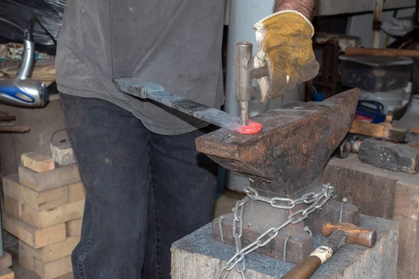 铁匠在铁锤上把一个洞开进了红色的热金属 — 图库照片