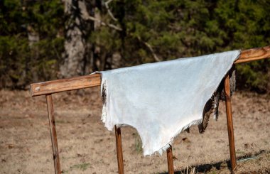 The whitetail deer has been harvested and with nothing going to waste, the hunter has cleaned the hide for tanning. The hide is draped over an outside railing to air out and dry. Bokeh effect. clipart