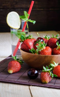 limon, kiraz, çilek ve ahşap bir arka plan üzerinde nane ile saf su bir bardak