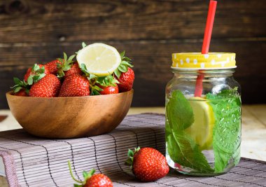 ahşap bir masada çilek ile nane ve kase ile limon suyu