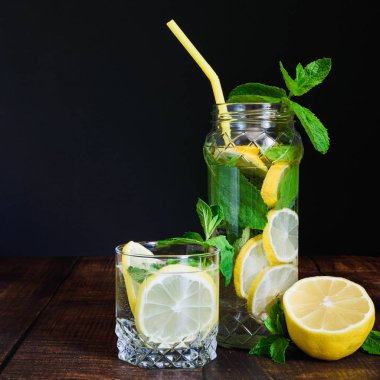 siyah bir arka plan üzerinde ahşap bir masa üzerinde nane ile limon suyu