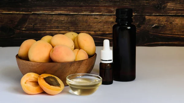 Aceite de semilla de albaricoque y albaricoque sobre una mesa blanca y fondo de madera — Foto de Stock