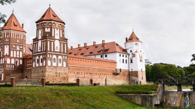 Belarus Mir kentinde kale Panoraması. Bir su kanalı üzerinde bir köprü ile bulutlu bir gökyüzüne karşı Kale.