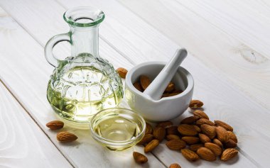 Almonds oil and peeled nuts on wooden table clipart