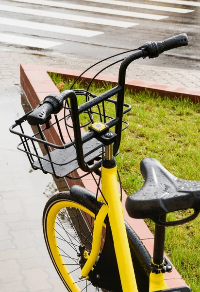 yellow bike with basket on the sidewalk after rain