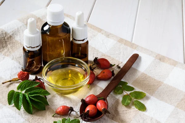 Kosmetik alami, produk ekologi alami, botol kaca komposisi dengan minyak rosehip, rosehip di atas meja kayu ringan — Stok Foto