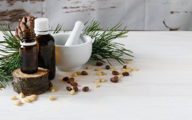 Çam fıstığı arkaplanlı sedir yağı kompozisyonu açık ahşap bir arka planda çam kozalağı ile