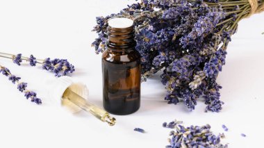 Beyaz arka planda lavanta yağı ve lavanta çiçekli cam şişeyi izole et.