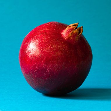 Yakın plan, olgun kırmızı nar mavi arkaplanda.