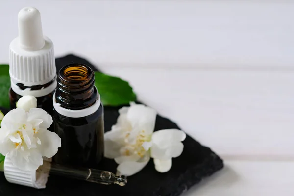 natural cosmetic product, jasmine oil with glass bottles on a wooden table