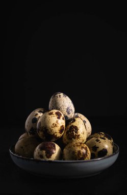 Bıldırcın yumurtaları bir tabakta, karanlık bir arkaplanda, yakın plan.