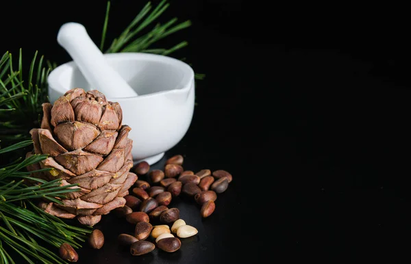 pine cone with nuts and mortar on a black background