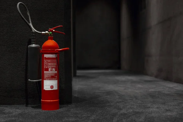 siyah zemin ve duvarlar arasında katta yangın söndürücü ayakta