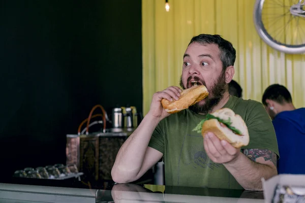 bir sandviç yiyor aç adam