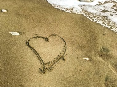 Deniz kıyısı tarafından çizilen dalgalar ve Kumlar çizilmiş kalp