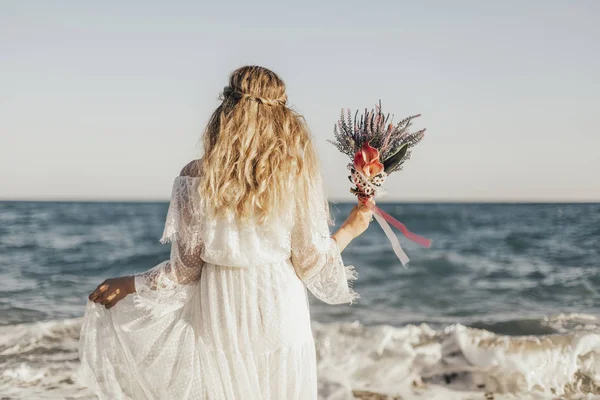 Deniz ve elinde çiçekler ayakta gelin