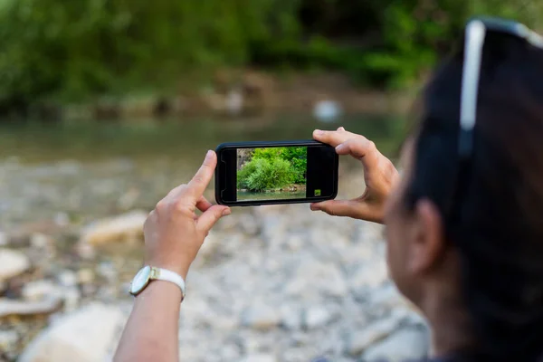 stock image Photographer woman taking photos in nature with cell phone