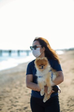 Genç bir kadın köpeğiyle kumsalda güneşleniyor.