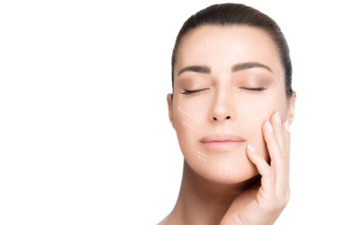 Yaşlanma önleyici tedavi ve estetik ameliyat konsepti. Güzel, genç bir kadın. Elleri yanağında. Yüzünde sakin bir ifade ve gözleri kapalı. Yüzünde beyaz oklar var. Mükemmel cilt. Beyaz üzerinde izole edilmiş güzel bir portre.