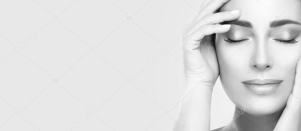 Monochrome beautiful young woman with fresh clean skin. Heathy skin woman gracefully holding her hands to face with serene expression and closed eyes. Cosmetology, beauty treatment or skincare concept
