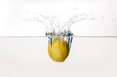 Telif alanı ve askıya alınmış su damlacıkları ile beyaz bir arkaplan üzerinden suya düşen taze sarı bir limonun hareketsiz görüntüsü.