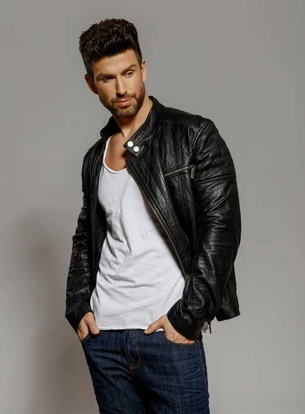 Handsome man in leather jacket on grey background