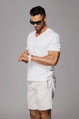 Yakışıklı yaz giysileri ve gri arka plan zamanında kontrol güneş gözlüğü