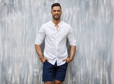 Beyaz gömlek giymiş ve gülümseyen yakışıklı erkek modeli