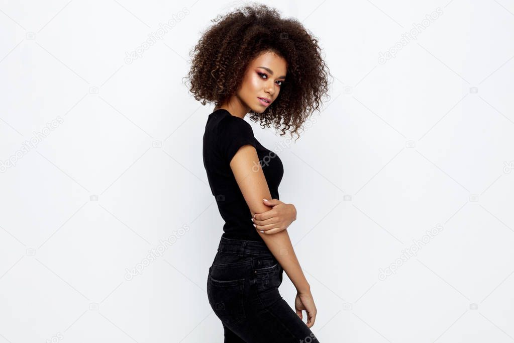 Beautiful african american woman with an afro hairstyle wearing black clothes and looking at camera isolated on white