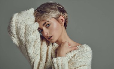 Kopya alanı ile gri arka plan üzerinde izole kamera bakarak sarışın kısa saç modeli ile genç kız portresi 