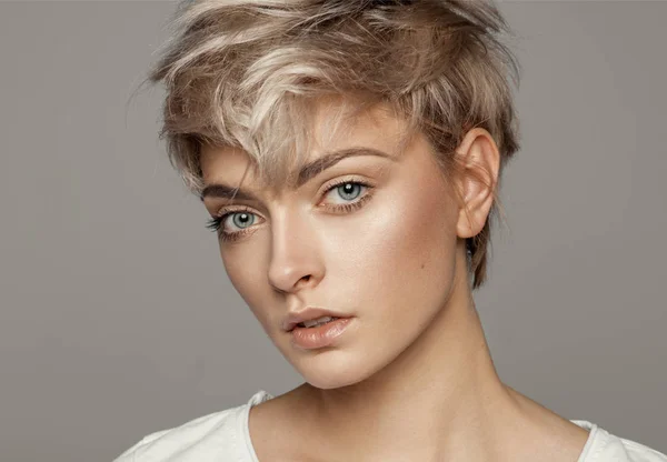 金髪の短い髪型をコピー スペースと灰色の背景に分離カメラ目線の少女の肖像画 — ストック写真