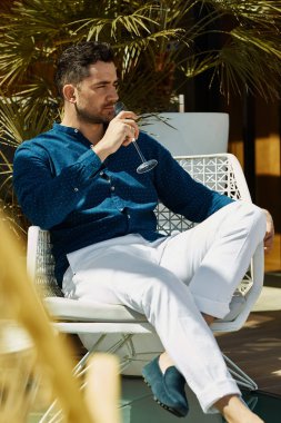 Yakışıklı model yaz kıyafeti açık rahatlatıcı ve beyaz şarap içme 