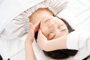 Yüz masajı yaptıran kadın ve pratisyenlerin elleri