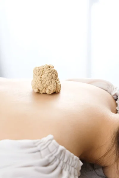 A large moxibustion placed on a woman's back in a bright acupuncture clinic
