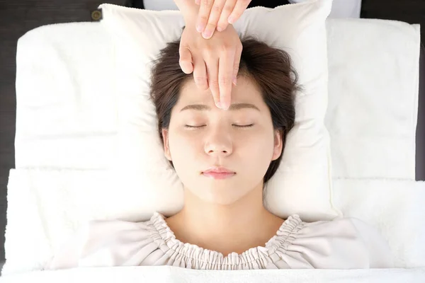 Woman receiving acupressure between the eyes at an acupuncture clinic