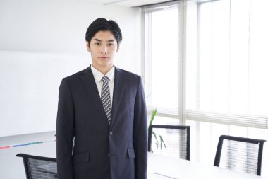 Japon bir erkek işadamı konferans odasında duruyor.