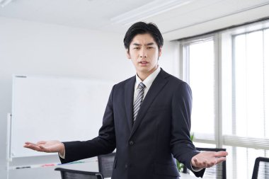 A Japanese male businessman discussing in a conference room clipart