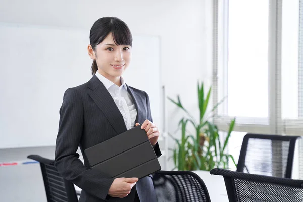 A Japanese female businesswoman with a tablet in her office