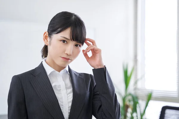 A Japanese female businesswoman struggling with her head in the office