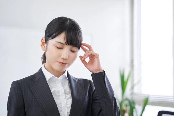 A Japanese female businesswoman struggling with her head in the office