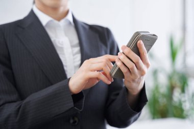 Japon bir kadın iş kadını ofiste telefonunu kullanıyor.
