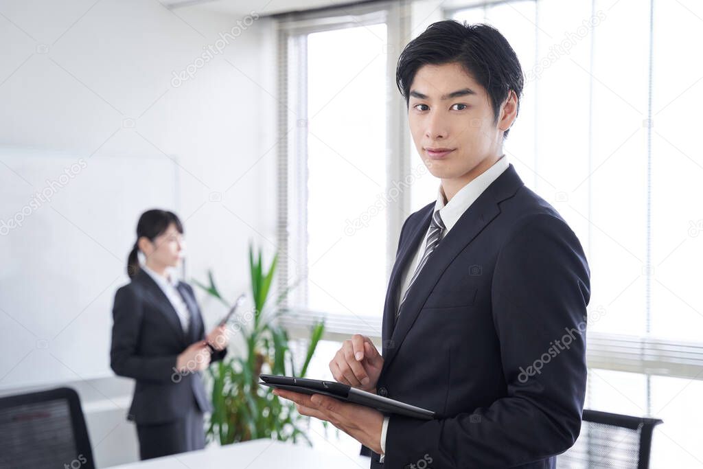 A Japanese male businessman smiles at the office