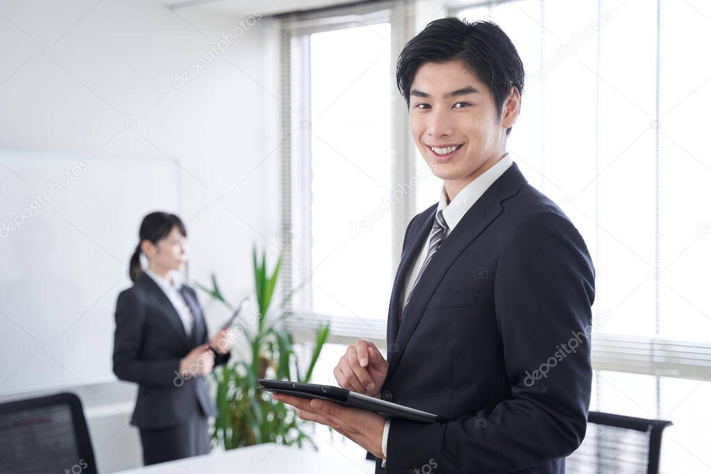 A Japanese male businessman smiles at the office