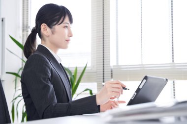 Japon bir kadın işkadını iş görüşmeleri için ofiste bir tablet kullanıyor.