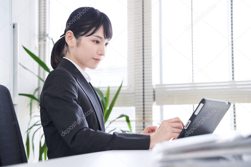 A Japanese woman who uses a tablet in her office to convert paper documents into data