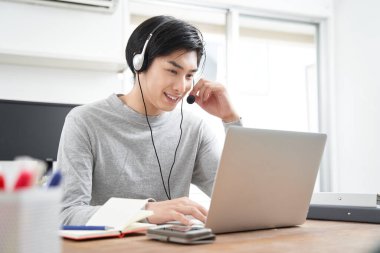 Sade giyinmiş Japon bir erkek işadamı evde online toplantılar düzenliyor.
