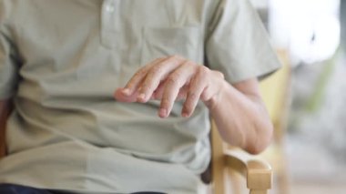 Elderly Asian man with trembling hands due to Parkinson's disease